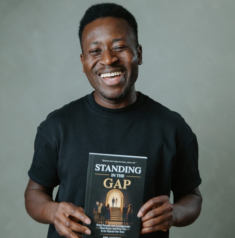 Eric Agyeman smiling and holding his new book, Standing in the Gap